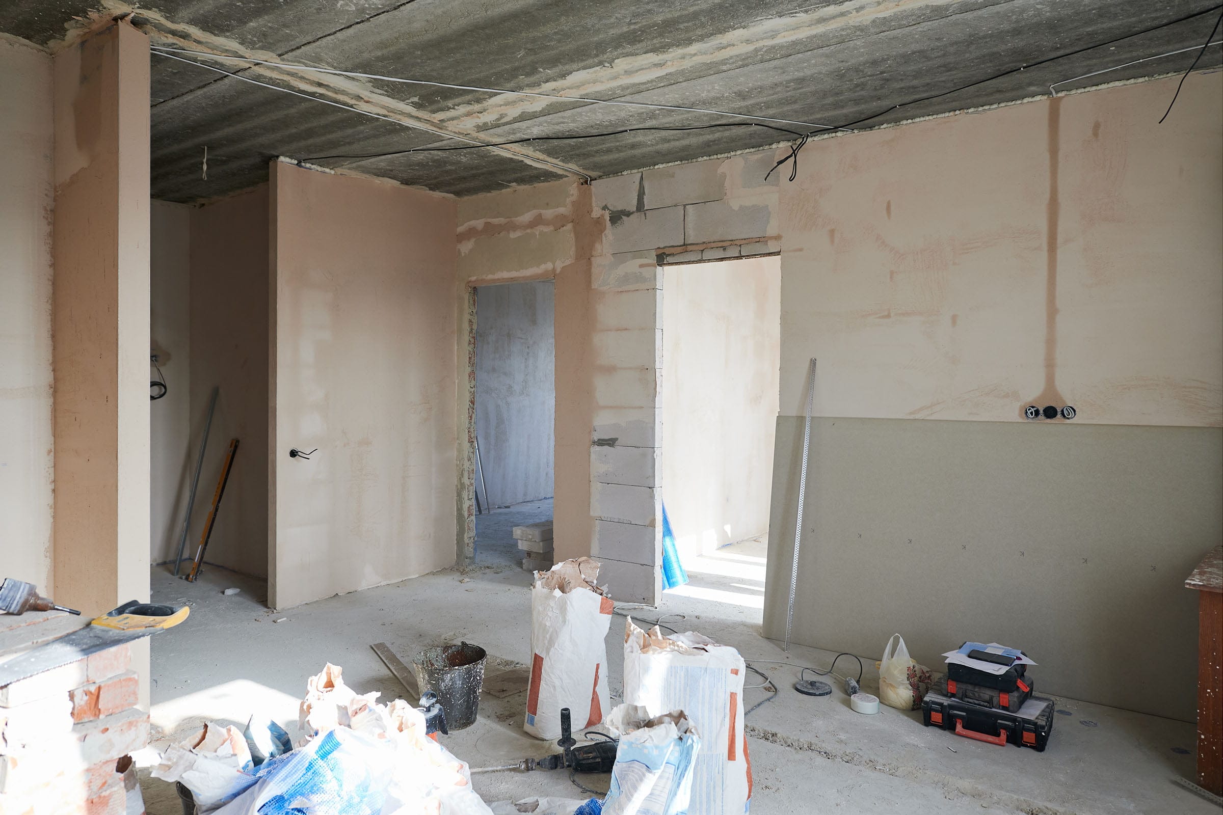 Interior renovation with plastered walls and construction tools.